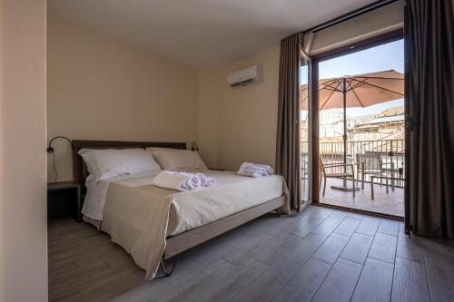a bedroom with a bed and a balcony with an umbrella at La Dimora Aragonese in Randazzo