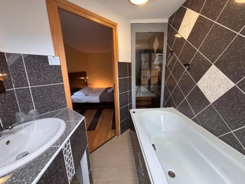 a bathroom with a bath tub and a sink at La Tour Des Lys in Maubeuge