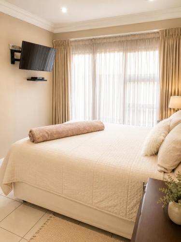 a bedroom with a large white bed with a window at Azania Bed & Breakfast in Meyerton