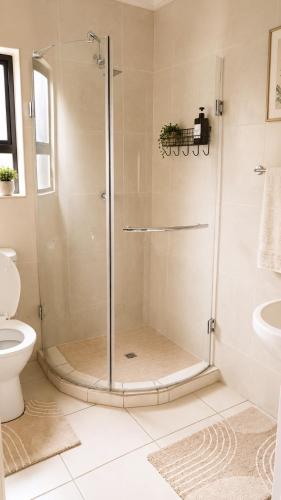a shower with a glass door in a bathroom at Azania Bed & Breakfast in Meyerton