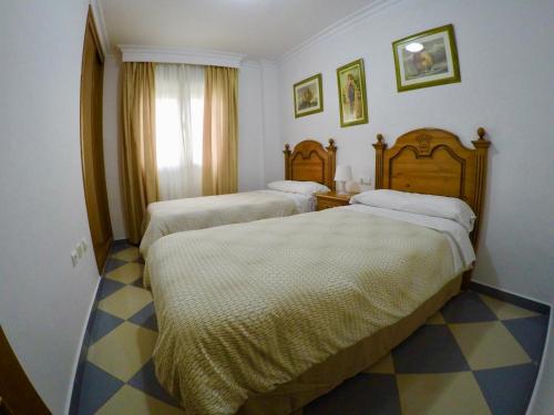 a hotel room with two beds and a checkered floor at Apartamentos Niña de Oro in Torremolinos