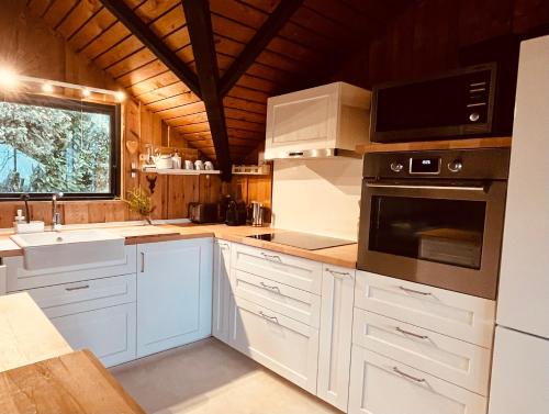 a kitchen with white cabinets and a sink and a microwave at Chalet - Kleines Paradies - in Appenzell
