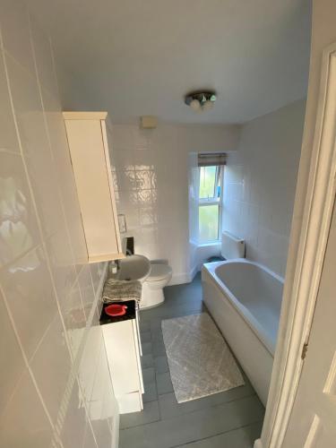 a white bathroom with a tub and a toilet at Strand Retreat in Tintagel