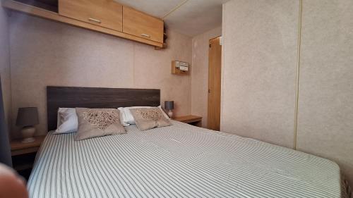 a bedroom with a large bed with two pillows at Mobile-home 4, 6 places in Quédillac