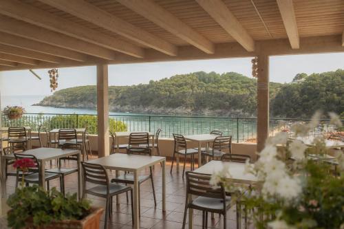 a restaurant with tables and chairs and a view of the ocean at Hotel Alma in Campo nell'Elba