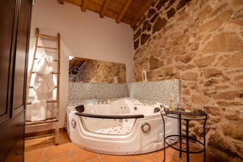 a bath tub in a bathroom with a stone wall at El Pajar de Tío Mariano in Tremedal