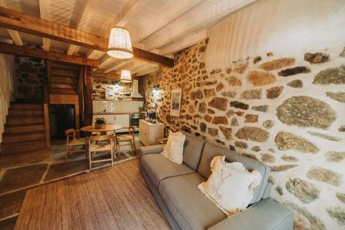 a living room with a couch and a stone wall at La casa del Mayoral in Tremedal