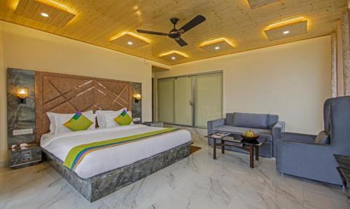 a bedroom with a bed and a couch and a ceiling fan at The Ortus Residency in Dharamshala