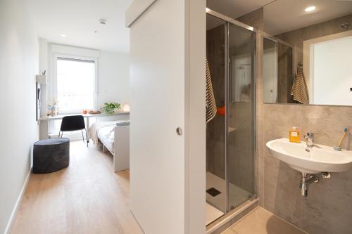 a bathroom with a sink and a shower and a bedroom at Canvas Valencia Burjassot in Burjassot