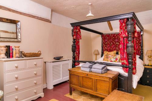 a bedroom with a four poster bed and a dresser at Finest Retreats - Lavender Cottage in Methwold