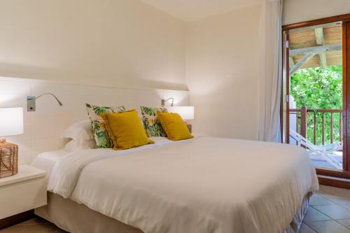 a bedroom with a bed with yellow pillows and a window at Villa Itzaga by muse villas in Post of Flacq