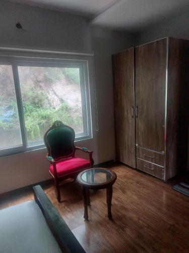 a room with a chair and a table and a window at White Ice Cottages in Mānsehra