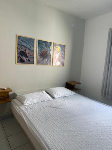 a bedroom with a bed with three pictures on the wall at Casa Branca in Prado