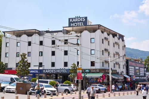ein großes weißes Gebäude an einer Stadtstraße mit Autos in der Unterkunft Kardes Hotel in Bursa