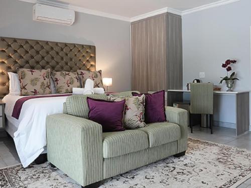 a bedroom with a bed and a chair and a couch at Meloding Guest House in Bela-Bela