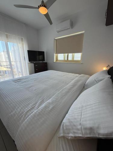 a white bed in a bedroom with a ceiling fan at Pearl House in Paralimni