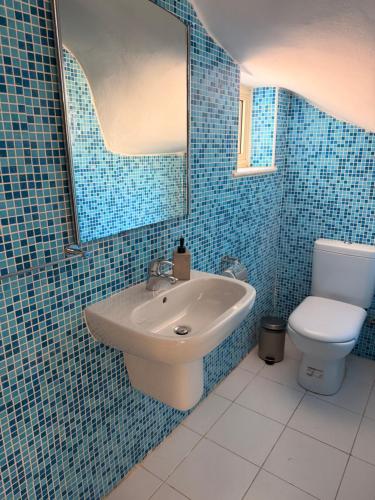 a blue tiled bathroom with a sink and a toilet at Pearl House in Paralimni