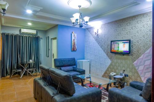a living room with couches and a flat screen tv at Navy Guest House, Kaduna in Kaduna