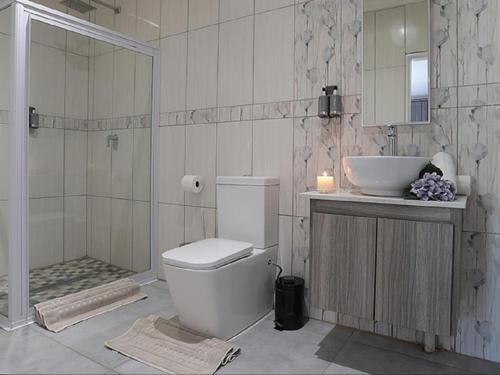 a bathroom with a toilet and a sink and a shower at Meloding Guest House in Bela-Bela