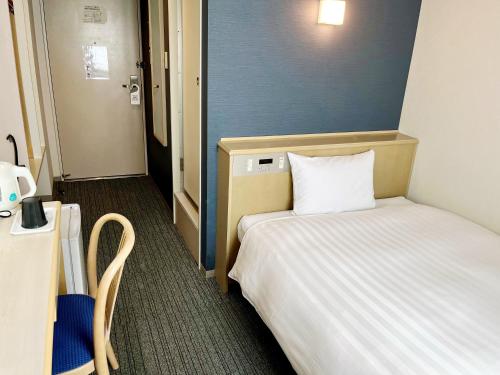 a small room with a bed and a table and chair at Hotel Premium Green Plus in Sendai