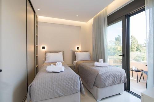 two beds in a room with a balcony at Glamour Residences 3-4 by CorfuEscapes in Análipsis