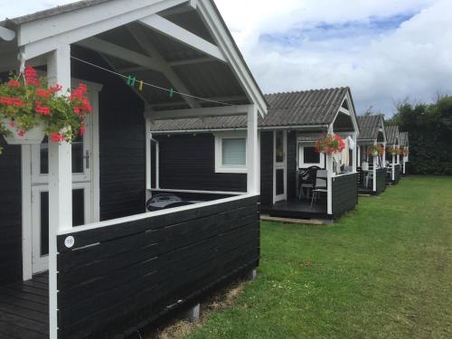 a row of cottages with flowers in a yard at Løkken Family Camping & Guesthouse in Løkken