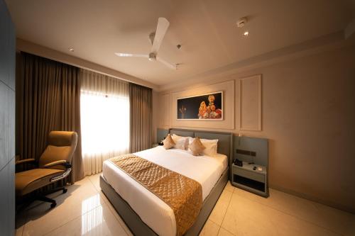 a bedroom with a bed and a chair and a window at Hanric by Eight Continents Amaranta, Varkala in Varkala
