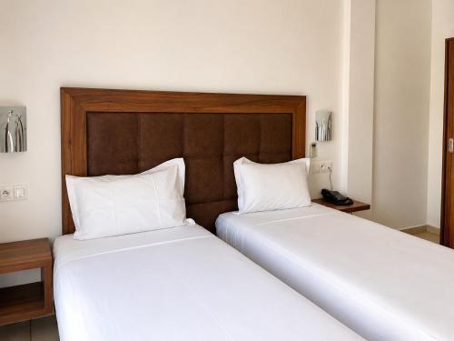 two beds in a hotel room with white sheets at Hotel Etoile Du Nord in Tangier
