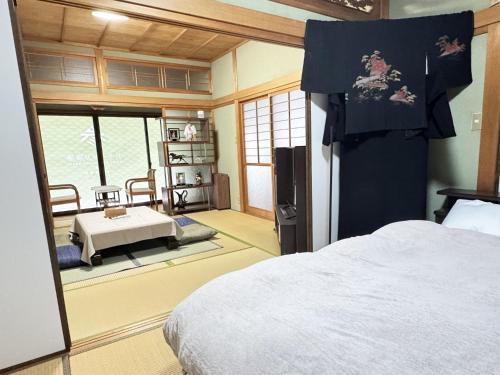a bedroom with a bed and a room with a table at おかげ参り宿場 in Ise