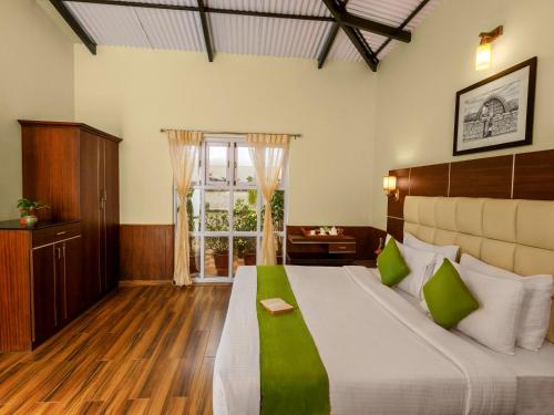 a bedroom with a large bed and a window at Rosewood by Nature Resorts and Stays in Ooty