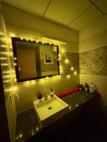 a bathroom with a sink and a mirror with lights at Novastay in Greater Noida