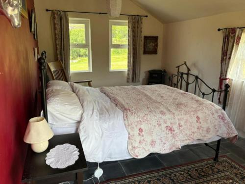 a bedroom with a bed and a table with a lamp at Glenmore Cottage - Waterville in Waterville