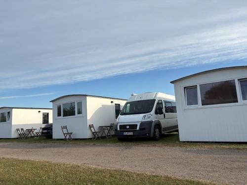 a van parked in front of three mobile homes at Løkken Family Camping & Guesthouse in Løkken