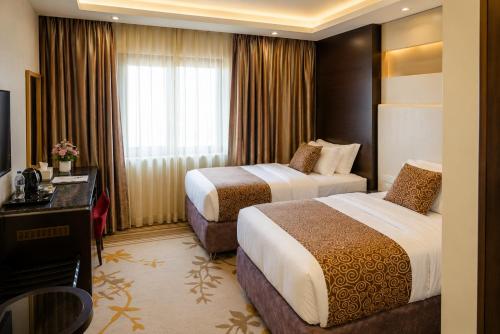 a hotel room with two beds and a television at Attawfeek Plaza in Tripoli