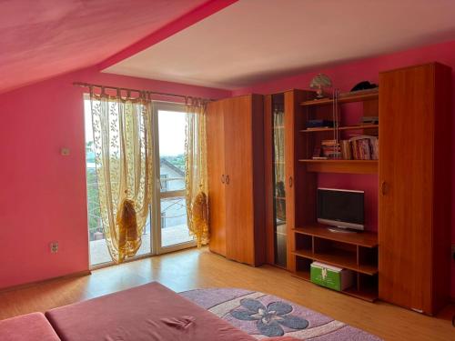 a living room with pink walls and a large window at Vila Nana in Râmnicu Vâlcea