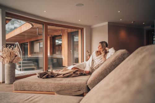 a woman sitting on a couch in a living room at Naturhotel Outside in Matrei in Osttirol