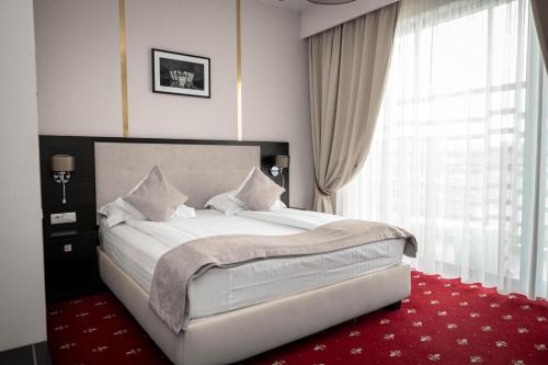 a bedroom with a large white bed with a red carpet at Salis Hotel & Medical Spa in Turda