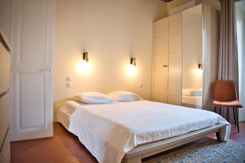 a bedroom with a white bed and a chair at Elegant apartment with balcony - Maison Comte in Uzès
