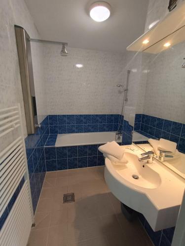a blue tiled bathroom with a sink and a tub at Hotel Rêve de la Vallée in Blesle