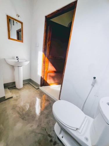 a bathroom with a toilet and a sink at Footmark Surf Stay in Pottuvil