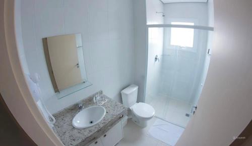 a white bathroom with a sink and a toilet at Hotel Toyo Inn in Boituva