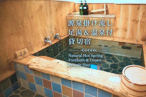 a bathroom with a tub and a sink in a room at 源泉掛け流し温泉付きの宇佐美貸切宿 お宿 喜喜哀楽 Oyado Kikiairaku #IG2 in Ito