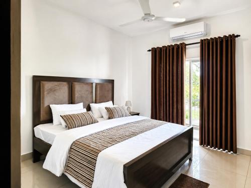 a bedroom with a large bed with brown curtains at Signature 2BR - Deluxe - Santorini - Negombo in Negombo