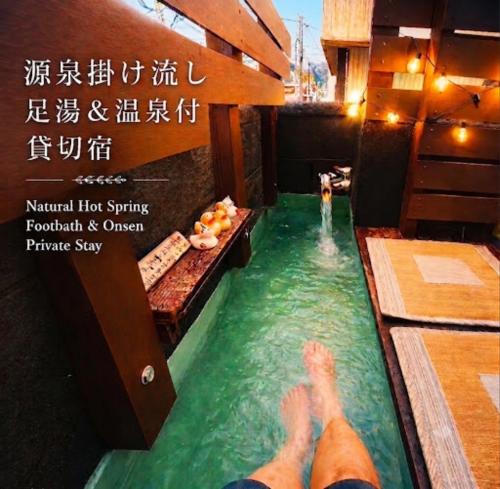 a person in a swimming pool with their feet in the water at 源泉掛け流し温泉付きの宇佐美貸切宿 お宿 喜喜哀楽 Oyado Kikiairaku #IG2 in Ito