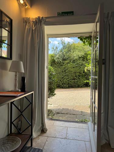 an open door leading to a patio with a yard at Stunning stone cottage on Bath's doorstep in Box