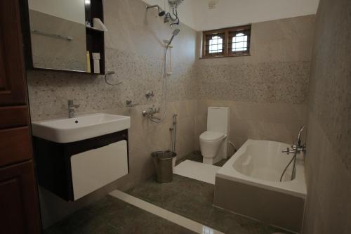 a bathroom with a sink and a toilet and a tub at Cosy Concepts in Kovalam