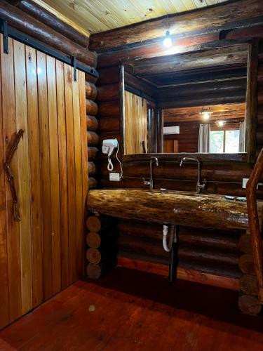 a bathroom with a sink in a log cabin at Hotel & Restaurant Las Brisas in Puerto Esperanza