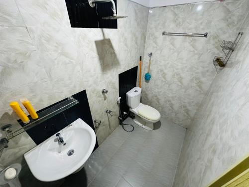 a white bathroom with a sink and a toilet at The Shire in Kandy