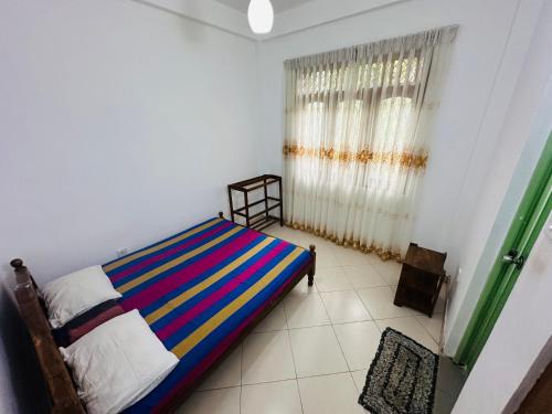 a bedroom with a bed with a colorful striped blanket at The Shire in Kandy