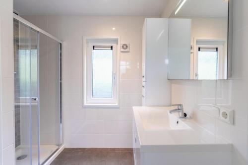a white bathroom with a sink and a shower at Resort Kagerplassen in Warmond